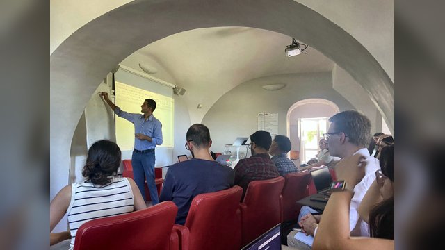 Marcello Montanino explaining a slide on human driver longitudinal modelling to participants seated in a vaulted classroom