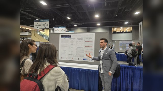 Davide Iannelli explaining a car-following poster to two visitors at TRB 2025