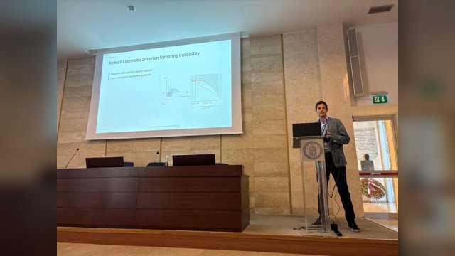 Marcello Montanino speaking at a lectern beside a projected slide showing diagrams of string instability